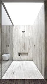 The shower is enclosed in travertine and topped with a skylight.

