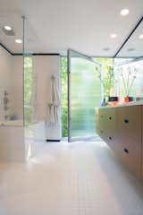 In the master bathroom, a large pivot door creates gracious indoor/outdoor flow.