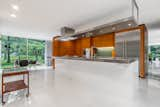 Kitchen, White, Wall Oven, Cooktops, Recessed, Refrigerator, Range Hood, Wood, Concrete, and Metal Unimpeded glimpses of the surrounding property via generous sight-lines and copious glazing.  Kitchen Wall Oven Refrigerator Concrete Metal Photos from A Mint Midcentury in New York Asks $2.2M