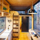 Kitchen, Pendant Lighting, Refrigerator, Medium Hardwood Floor, Wood Cabinet, Drop In Sink, Wood Counter, and Cooktops The upper loft has another mattress, so the tiny home can comfortably sleep up to four. Linens are included in the rental.

  Photo 5 of 7 in Unplug at This Off-Grid Tiny Home in South Australia