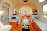 Living Room, Coffee Tables, Medium Hardwood Floor, Chair, Bench, Storage, Shelves, Rug Floor, and Ceiling Lighting White walls and a motif of wood accents create a stylish, neutral setting.

  Photos from Rent This Reimagined Airstream for Your Next Shindig
