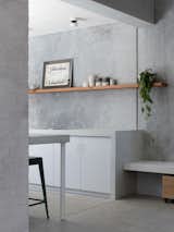 Kitchen, Concrete Counter, Ceiling Lighting, Concrete Floor, White Cabinet, and Concrete Backsplashe The entrance to the galley kitchen, with the tile repeated below the built-in bench.  Photo 6 of 10 in A Carbon-Neutral Concrete House Is an Exemplary Infill in Western Australia