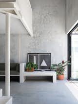In defiance of its oversized neighbors, this sustainable 753-square-foot home in Perth, by architecture firm Whispering Smith, maximizes its small footprint through built-in furniture and textures of concrete, reclaimed brick, tile, and white metal. Devoid of walls and doors, the streamlined spaces flow into one another, and connect to the ample rear courtyard. 