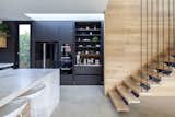 Kitchen, Marble Backsplashe, Refrigerator, Microwave, Concrete Floor, Wood Cabinet, Wall Oven, and Marble Counter A detailed shot inside the pantry shows how it corrals counter clutter and hides small appliances.  Photo 7 of 11 in A Streamlined Addition Serves a Family of Four in Australia