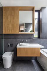 Bath Room, One Piece Toilet, Drop In Tub, Vessel Sink, and Marble Counter Oak cabinetry topped with marble continues the kitchen's themes in a bathroom.  Photos from A Streamlined Addition Serves a Family of Four in Australia
