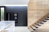 Kitchen, Concrete Floor, Refrigerator, Marble Counter, Wall Oven, Microwave, and Wood Cabinet A bank of pantry cabinets are clad in the "Ravenswood" panels to disguise sleek, black appliances.  Photos from A Streamlined Addition Serves a Family of Four in Australia