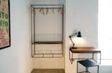 A sleek wall-mounted closet and a small desk, both fashioned from steel and wood, save space in a smaller room. 
