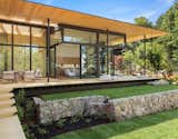 A stone retaining wall provides a level base for lush grass. 