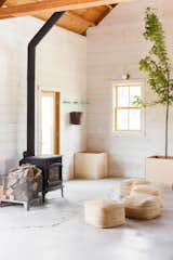 Shiplap pine walls, primed white, complement unfinished concrete floors and a wood stove by Jotul.