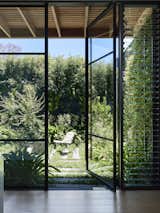 A wall of glazing across from the kitchen pod connects to a centrally located courtyard, with landscaping by Eckersley Garden Architecture.