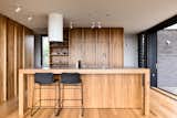 "The kitchen appears as a central bench, acting as social knuckle to the interior space," says the firm.