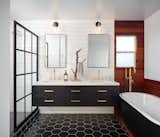 The palette of white, black, and brass continues in the principal bathroom.