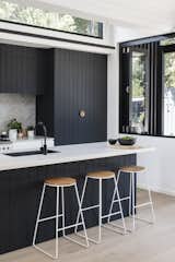 The dark kitchen cabinetry is a nod to the exterior, "as the pattern of the shiplapped cladding informed the grooves of the kitchen joinery," says the firm.