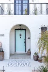 The entryway of this Sacramento home features new concrete embellished with a cement tile pad. It brings "an extra layer of texture when you walk in," says owner and designer Christina Valencia. Spindles were added to the restored second-floor railing for safety, before it got a new coat of paint. All-new lighting makes the exterior more welcoming, as does the refreshed front door, thanks to its new light blue color.