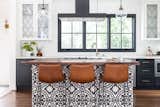 The new kitchen has much more elbow room and an eat-in bar clad in graphic, black-and-white tile. Carrera marble tile laid in a herringbone pattern covers the backsplash, while the counters are honed marble, at the back, and walnut, at the island. 