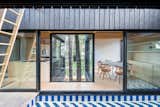 The kitchen and dining area are separated by a glassed volume that wraps two mature trees. “The views from the house are defined precisely by materiality so that the forest seems to enter the house,” said the firm.