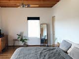 The bedroom maintains the simple palette with windows fabricated by the homeowner and Brazilian walnut flooring.