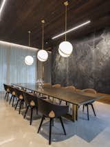 Marble slabs adorn the wall, and bespoke lighting illuminates the table in the dining room.