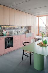 In the kitchen area of Berlin-based architect Ester Bruzkus's apartment, dusty pink cabinets are topped with a terrazzo counter and backsplash with integrated shelf. Gold accents, via the canisters, flatware, and faucet, lend a little glam.