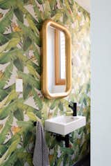 The powder room features Botanica Jungle Fever wallpaper by Emily Ziz.