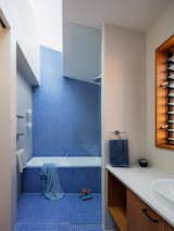 Brilliant blue tile from Classic Ceramics cascades down the wall, wraps the tub, and covers the floor in the kids' bath.