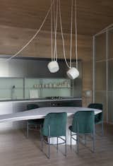 In the kitchen/dining room, a mint backsplash syncs with emerald Etel "AL" chairs. The ceiling light is the Aim by FLOS.
