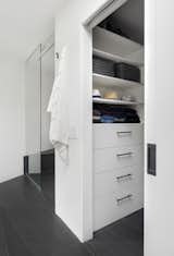 "Previously, the closet was not a walk-in and was stuffed head to toe with clothes," says Wise. "We carved out space from the hallway and created a walk-in that was outfitted from top-to-bottom with functional storage." A pocket door hides the interior when needed. The shower is in the same space as before, but lengthened so that Wise could use the awkward angled wall for a shower bench.