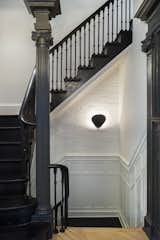Now, the stairs and railing are painted Pitch Black from Farrow & Ball and a Gubi Cobra wall sconce illuminates the way.