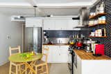 In the garden apartment kitchen, IKEA cabinet boxes received fronts from Reform, in the Basis style. An Andrew Neyer Barbell Pendant echoes the black two-inch hex wall tile. The black wire and wood open shelves are the client’s own and similar to the String Pocket Shelf, says the firm.  