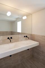 The main bathroom is clad in travertine and maintains the understated color palette found throughout the home.