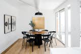 In the dining room, the BAZZ Loft matte black pendant light is suspended over the Shoreditch dining table from CB2 and Nomad chairs from Industry West. The Gold Rush Poster is by Jessica Rae Sommer.
