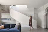 A sweeping ribbon staircase leads up to the second-floor bedrooms and rooftop deck.