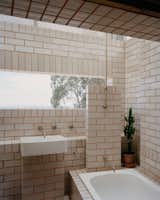 In the bathhouse, "clay bricks slip-glazed on two sides are laid with contrasting mortar to match the raw clay color of the other sides," says the firm.