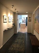 Now, the front entry leads to a vestibule with two doors, one which accesses the main floor residence here, and one which leads up a flight of stairs to the second-floor apartment. Once inside the main residence, there is this entry gallery, which has two bedrooms and a bathroom off it, and leads to the open-plan living area.
