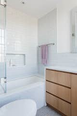 Now, the bathroom flows cohesively with the rest of the home, thanks to simple white tile and a custom wood vanity.