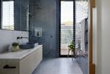 The upstairs bathroom echoes the palette of the downstairs one, with Fibonnaci steel cement tile on the floor, and blue Perini Bagette tile on the walls.