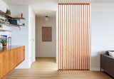 A vertical grain fir wood screen separates the stairs from the main living area. The credenza and shelving are original to the house.