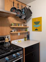Ben fashioned the stove-side cabinet as a freestanding unit. This area functions as the couple’s main prep space, and a deep drawer below holds bigger appliances like the food processor and a stock pot. The custom pot rack is by Kari Merkl of the local design and manufacturing company Merkled Studio. 