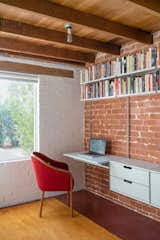 This room is located in a brick addition that the architects estimate was built in the 1950s. "Because this space was an addition and of a different material and construction than the original home, we felt exposing and celebrating this difference would be best," says Hazelbaker. They did so by removing a built-in closet, exposing the brick wall, and installing the Vitsoe system that doesn’t obscure the difference between old and new.