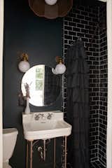 In the smaller bathroom, Rossi embraced the cozy with dark paint and subway tile.