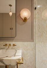 The bathroom features an alabaster and unlacquered brass Melange sconce by Kelly Wearstler.