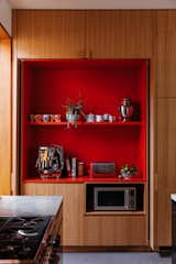 After: Bright-red laminate shelves hold the family’s coffee supplies inside the custom blackbutt cabinetry.