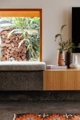 The concrete bench meets the wood of the built-in media cabinet. The floors are also concrete, poured to match the existing floors in the kitchen.