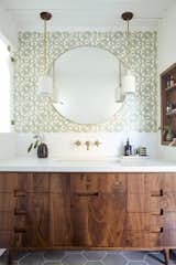 A walnut vanity is topped with a Silestone White Zeus quartz counter. The pendant lights framing the mirror are from Cedar &amp; Moss and the wallpaper is from Heath Ceramics + Hygge &amp; West. “We decided to add in some pops of color and pattern in the kids' bathroom with the bright tile, and then the master bathroom with that cool wallpaper,” says Foken.