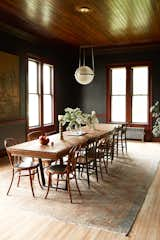 Walls painted Black Ink by Benjamin Moore set the tone in the dining room. The couple retained the original floors and beadboard ceilings, and left the woodwork as they found it. Nick built the table, which can seat 14, from a counter found in the barn, and the chandelier above it is from Rejuvenation.