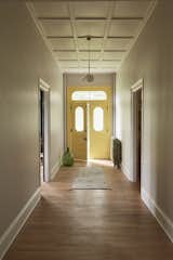 In the revitalized hallway, an IC Light S by Michael Anastassiades for Flos hangs over the front door, painted Benjamin Moore Yellow Highlighter.