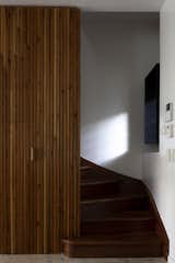 Seventy percent of the wood used for the paneled accent wall was recycled, and the installation extends to the salvaged staircase. The white terrazzo floors cover the entry as well.