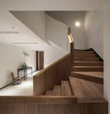 The wood staircase is capped with a smooth brass handrail.
