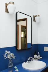 Crisp white paint modernizes the preserved cobalt blue counter. The mirror is from Rejuvenation.