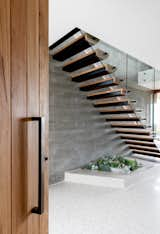 In the entry, an inset planter in the polished concrete floors sits beneath the open-tread staircase.